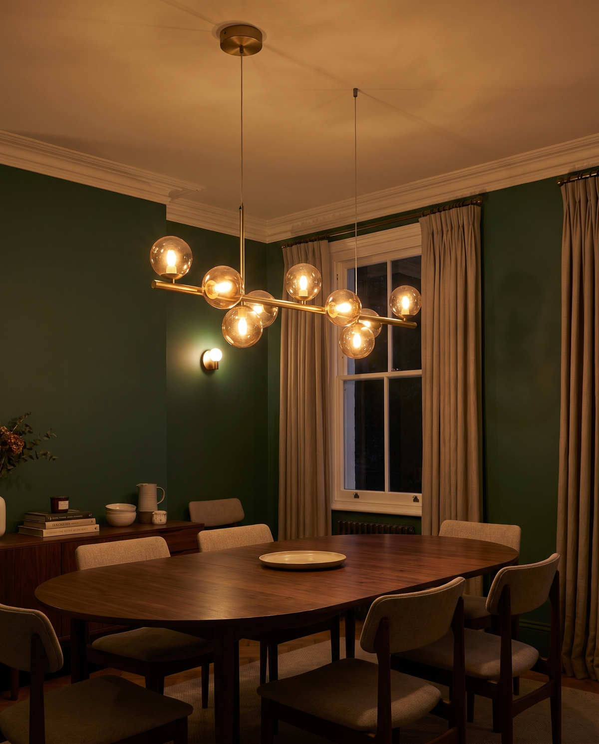 Barnes linear glass globe chandelier, cognac globes, lit above a walnut table in a green Victorian dining room