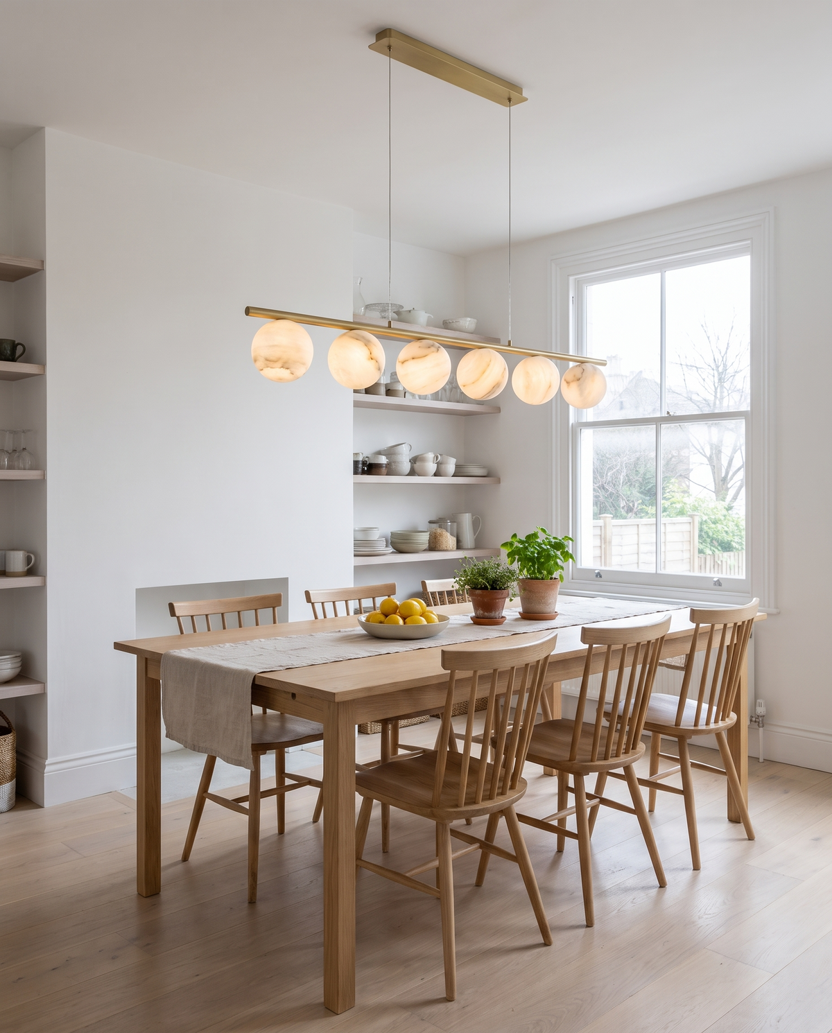 Battersea alabaster linear pendant in brass above an oak dining table in a bright kitchen