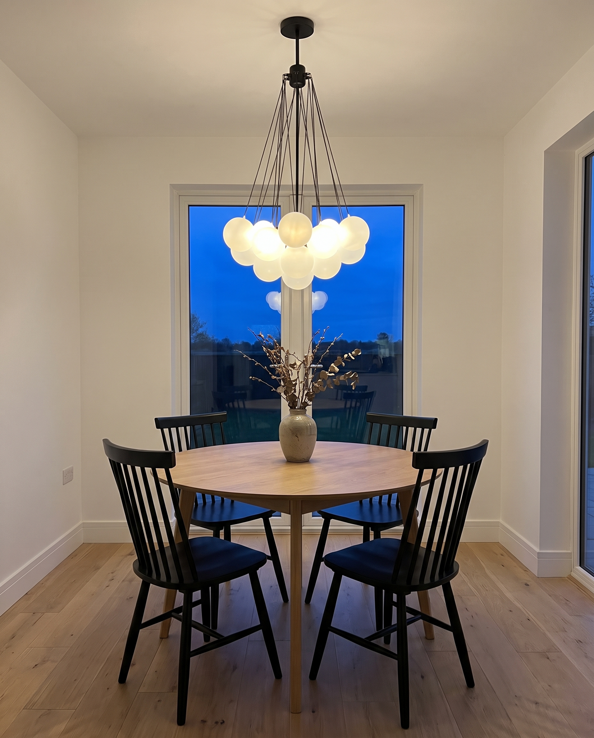 Putney bubble chandelier in black, lit above a round oak dining table