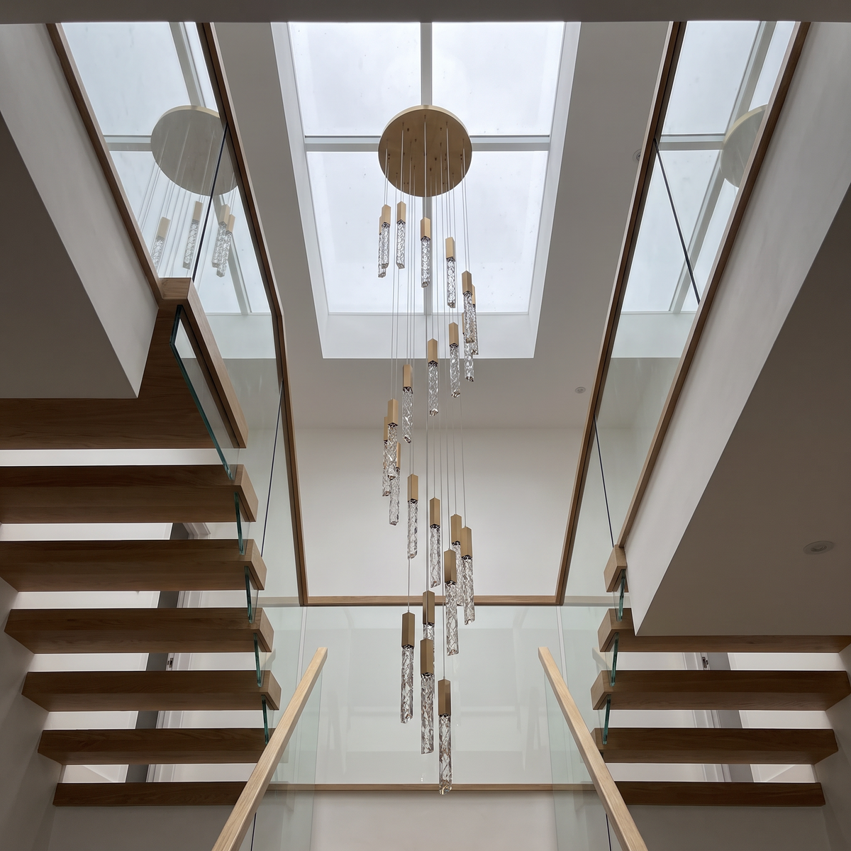 Somerset spiral crystal chandelier in a modern stairwell under a skylight