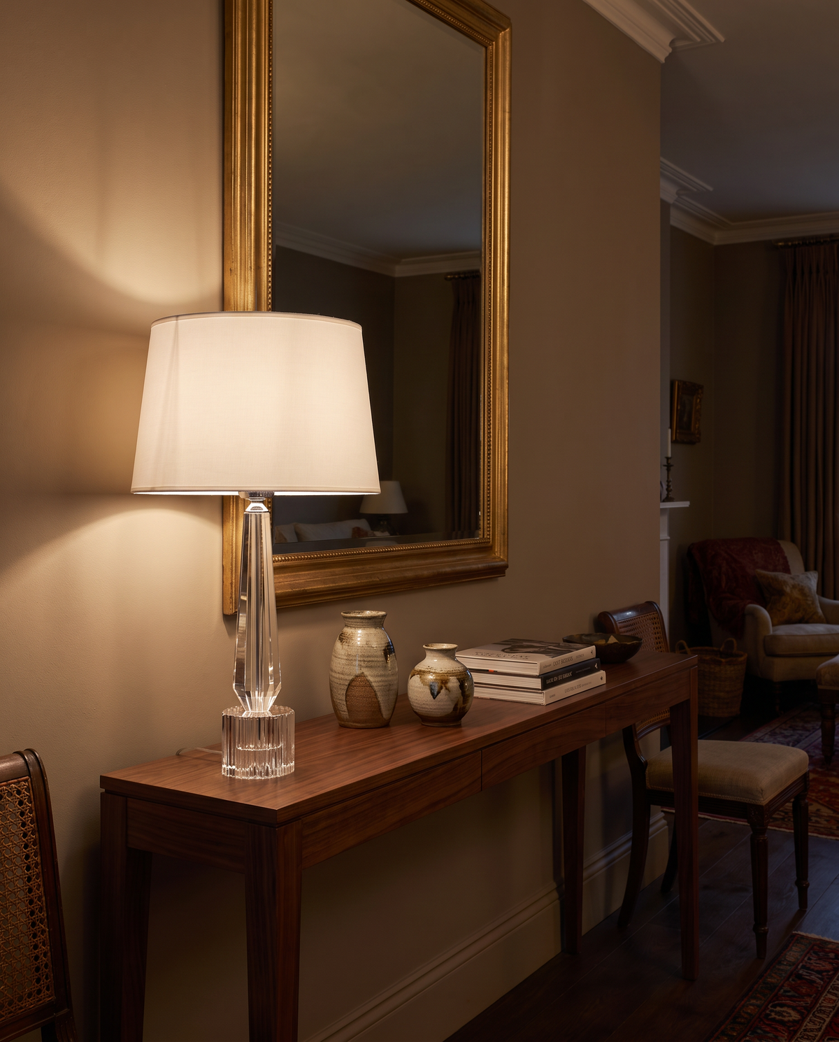Westminster crystal column table lamp lit on a walnut console