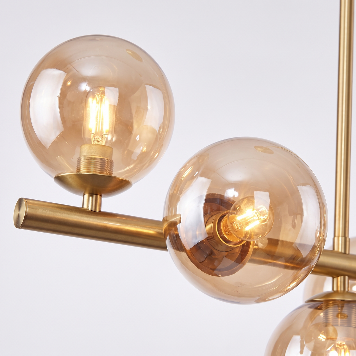 Barnes linear glass globe chandelier, close-up of the cognac glass globes and brass arms