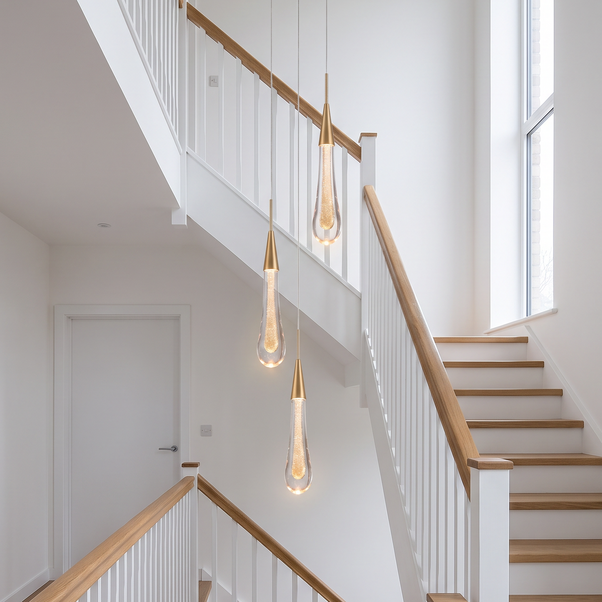 Islington crystal teardrop pendant light, three in gold hung at different heights in a stairwell